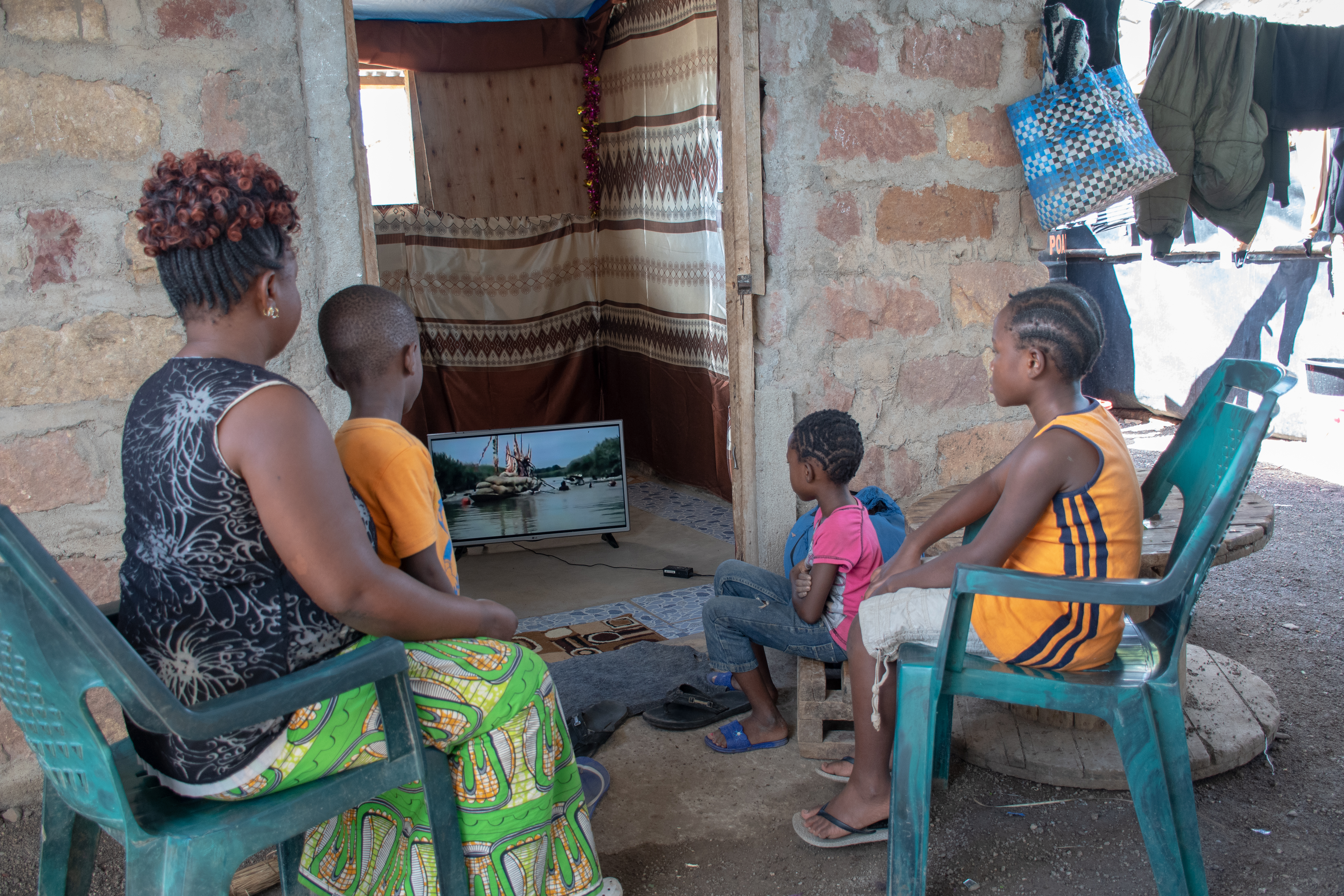 Sauda Meli watches television with her children at her home in Kalobeyei Village. The advent of the mini grid has enabled households in the area to access lighting and power at affordable rates.