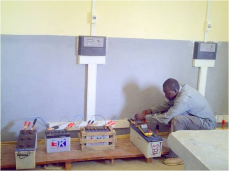 An operator of a solar battery charging station in Mali connects a battery to the charging terminal