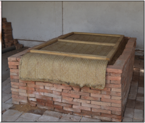 An evaporative cooling chamber (ECC) constructed from bricks with a cover made from dry grass and wood